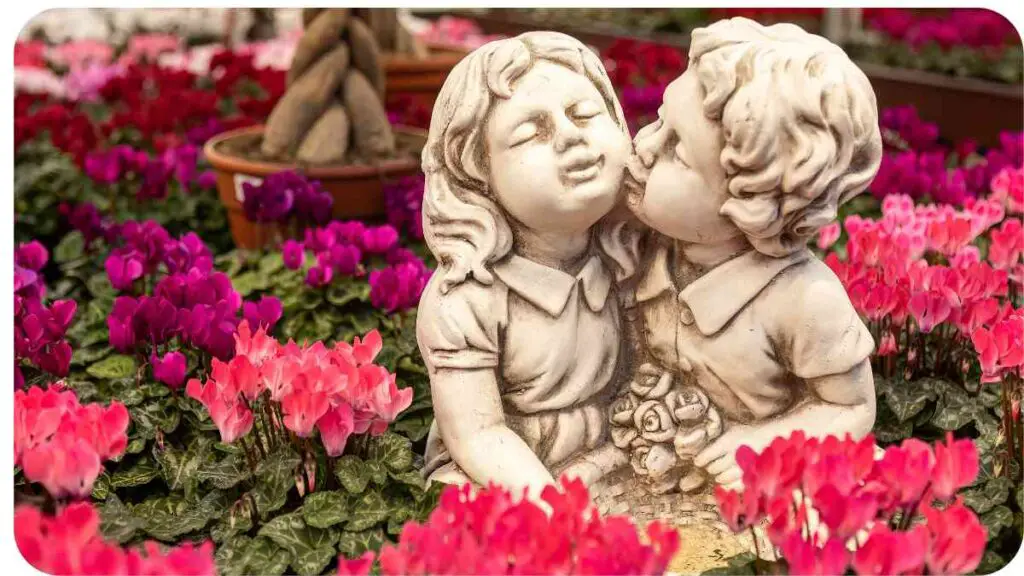 a statue of two children kissing in a flower garden